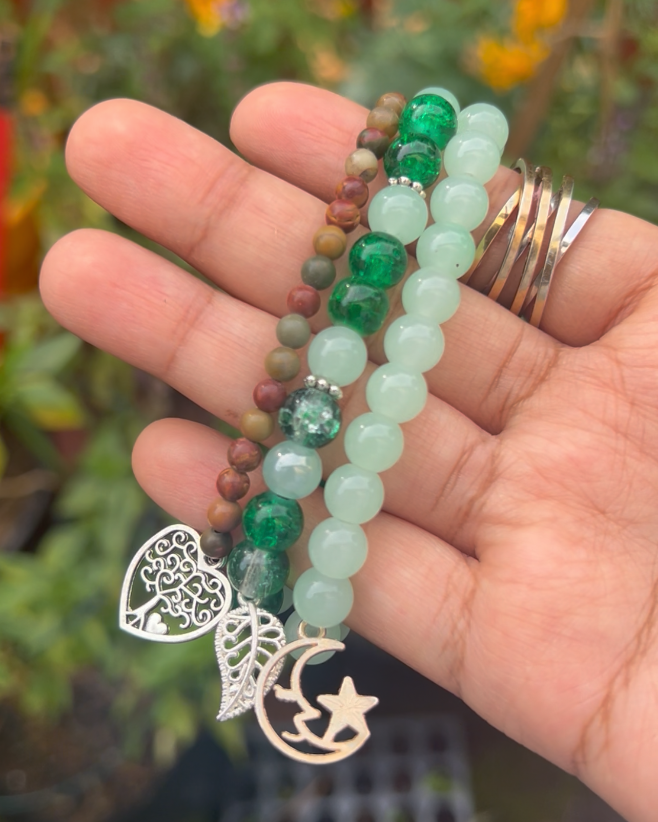 Hand holding a set of beaded bracelets with a blurred natural background