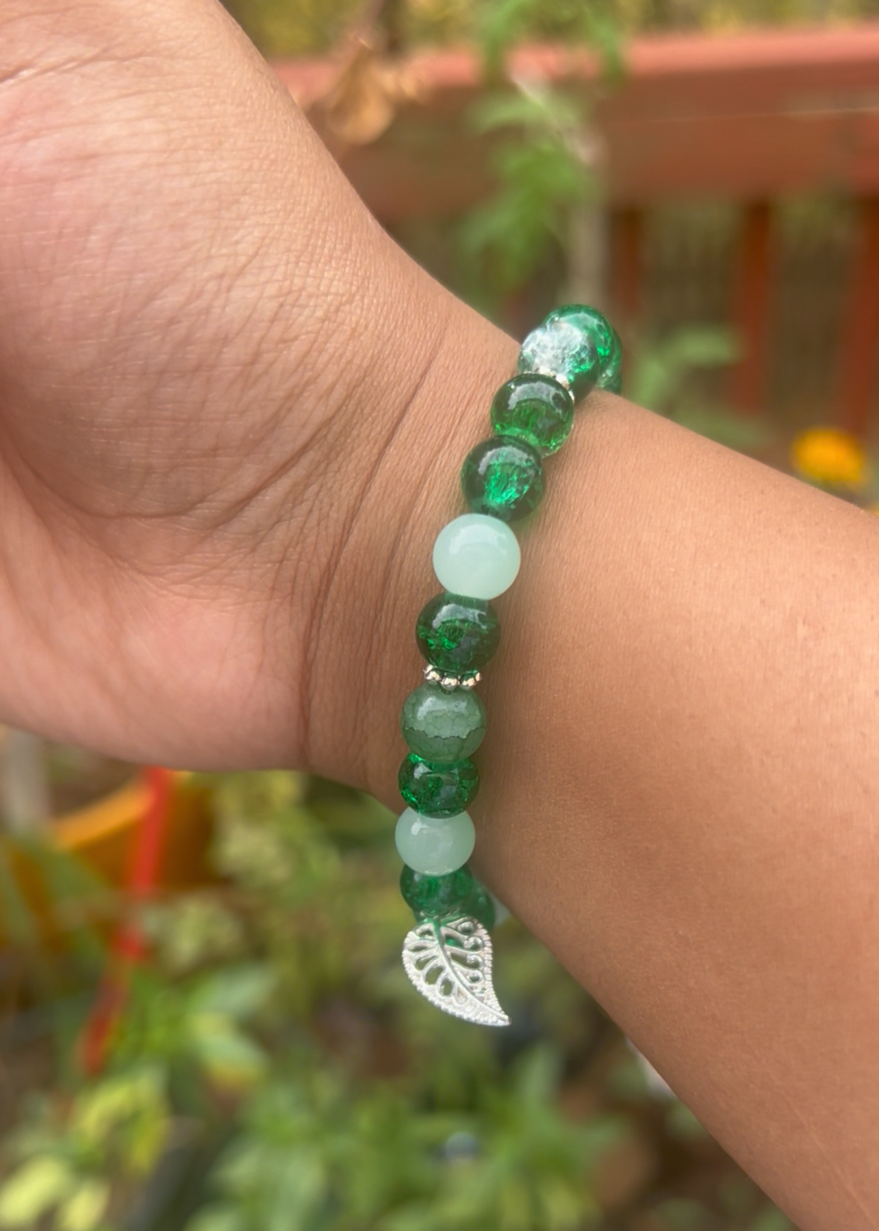 Green beaded bracelet on a wrist with a blurred background